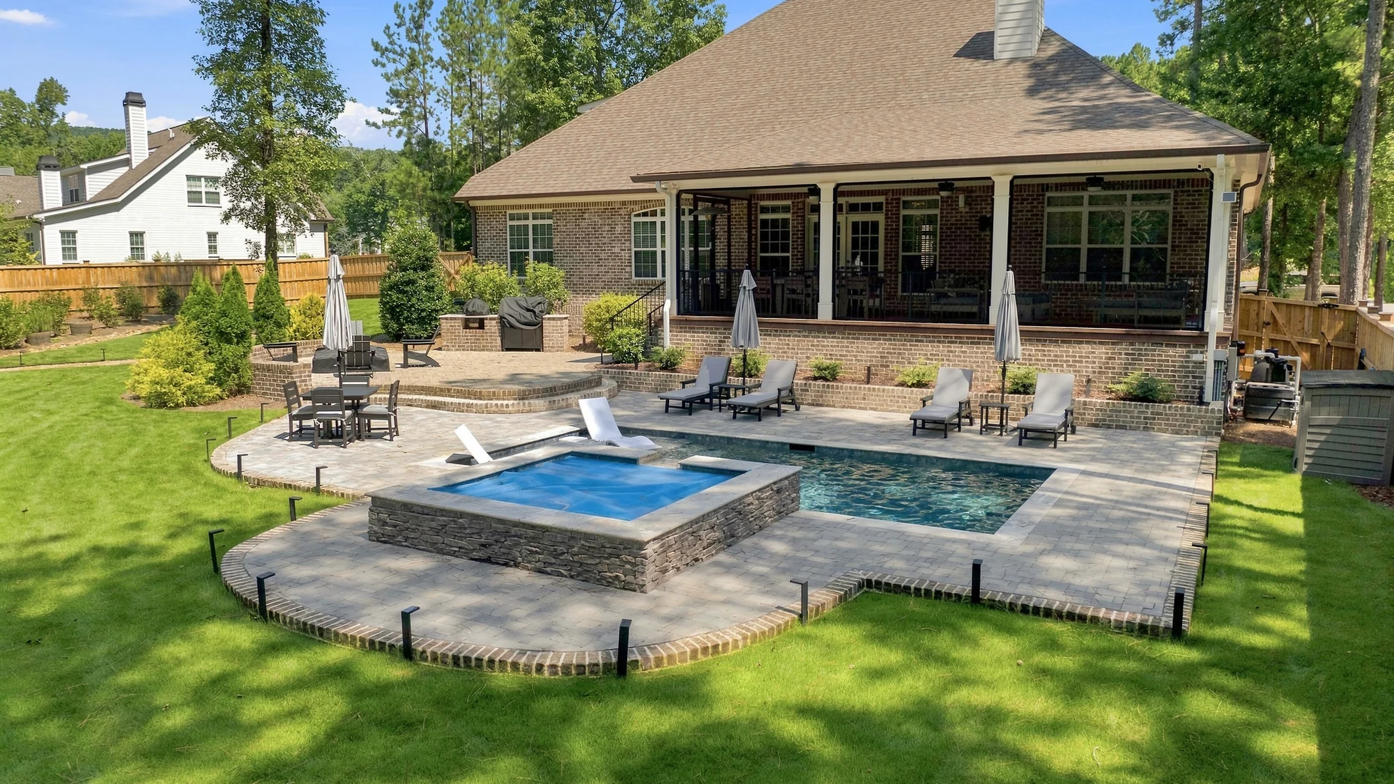 A finished BDS Landscape Co. pool terrace on Snead Avenue in Rome, Georgia: a two-level paver terrace, raised spa and wood privacy fence